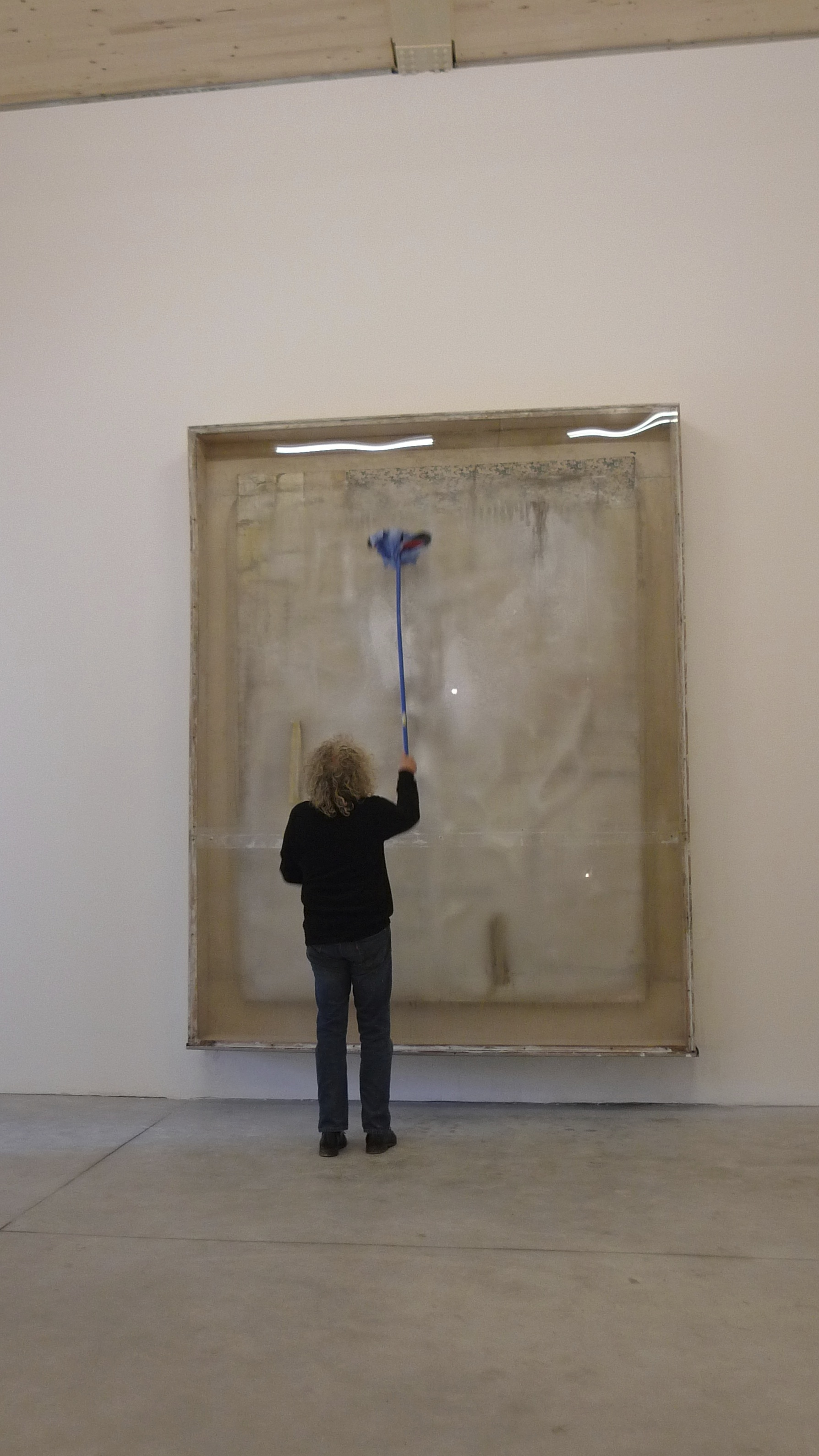 Australian-born painter Lawrence Carroll wiping off the condensation from his refrigerated work at the Pavilion of the Holy See